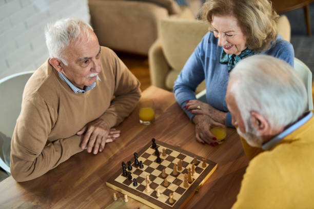 Happy senior friends playing chess at home Happy mature friends playing chess at home friends playing chess stock pictures, royalty-free photos & images
