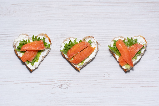 Heart-shaped sandwiches with cream cheese, salmon and lettuce.