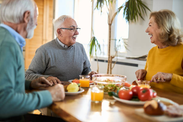 istock Group of happy seniors talking while having a meal at dining table. 2148056136