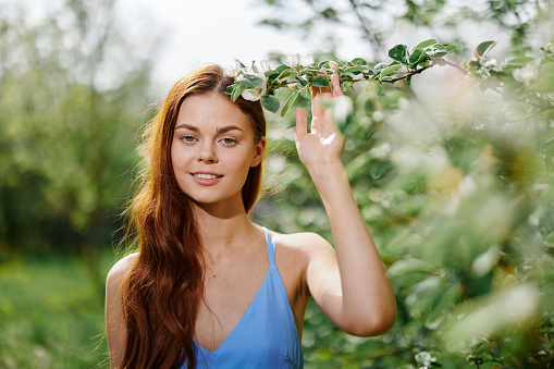 Woman portrait beautifully smiling with teeth spring happiness in nature against a green tree hand touch tenderness, safety from allergies and insects. High quality photo
