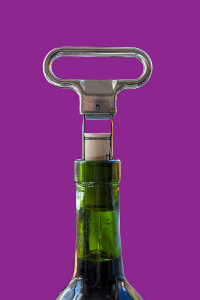 Green wine bottle with stainless steel two prong cork puller Two prong cork puller and cork halfway pulled from green wine bottle cork puller stock pictures, royalty-free photos & images