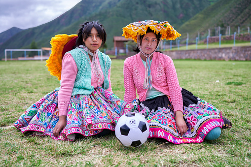 Portrait with a soccer ball of two women from Peru of Quechua ethnic group soccer players with the Andes in the background