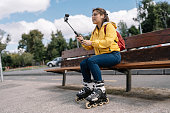 A girl is sitting on a bench with her skateboard and a camera