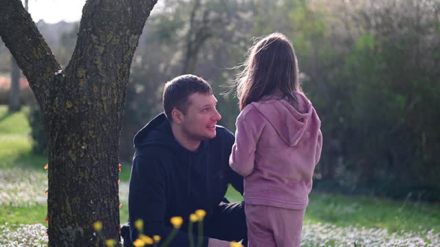 Smiling father playing with daughter in a parkland.