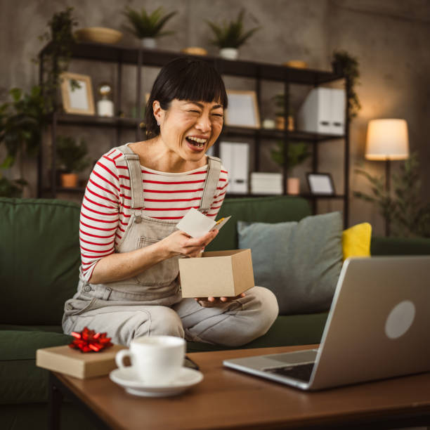 istock one mature woman open box presents and read card while on video call 2148065104