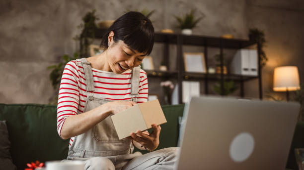 istock one mature woman open box presents and read card while on video call 2148065114