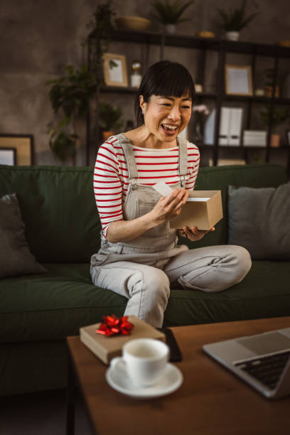 istock one mature woman open box presents and read card while on video call 2148065161