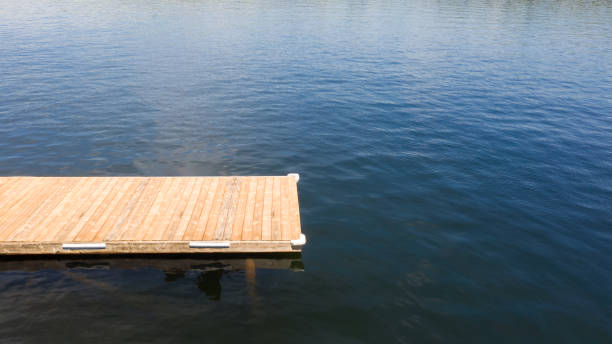 Wooden dock extending into the lake Tranquil lakeside scene with wooden dock at a Muskoka cottage in Canada floating dock stock pictures, royalty-free photos & images