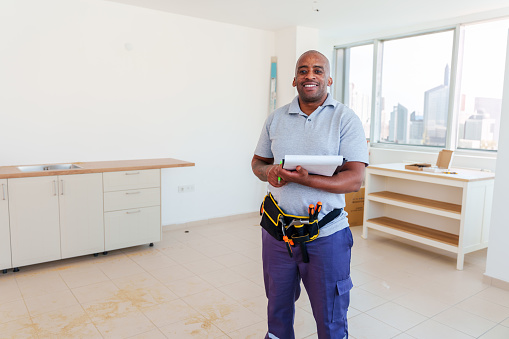 Architect man, clipboard and happy on construction site in industry, planning and inspection. Engineer, architecture and construction worker smile at industrial workplace in building, house or home