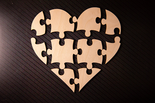 Alphabet letters on wooden square pieces forming heart shape on white background.