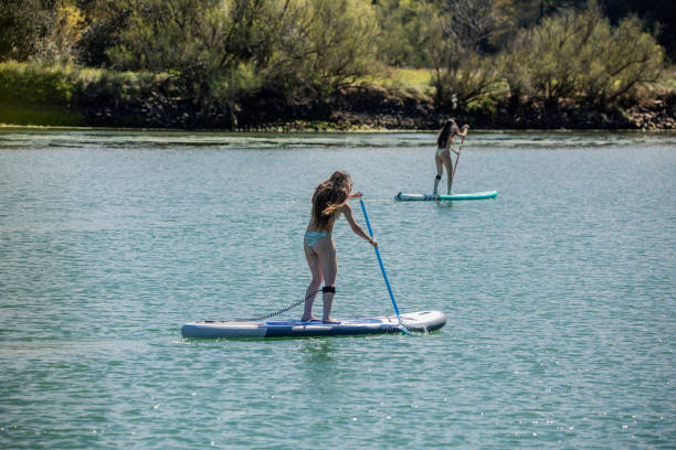 istock Multicultural Bikini-Clad Women doing paddle surf Together on Sunny Summer Lake 2148068571