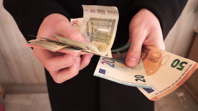 The hands of a man in a business coat count a stack of paper euro banknotes hanging in his hands. Successful Business deal, debt repayment, lending, Borrowing money, corruption, bribe
