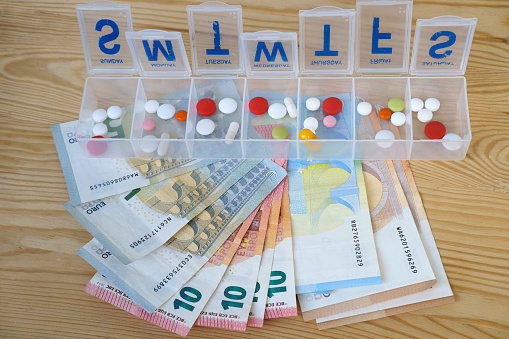 pills, capsules, vitamins in pillbox organizer for week, euro banknotes different denominations, concept controlling regular medication intake, organizing medication intake by patient, expensive drugs