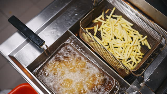 SLO MO Directly Above Handheld Shot of French Fries being Fried in Fryer at Commercial Kitchen