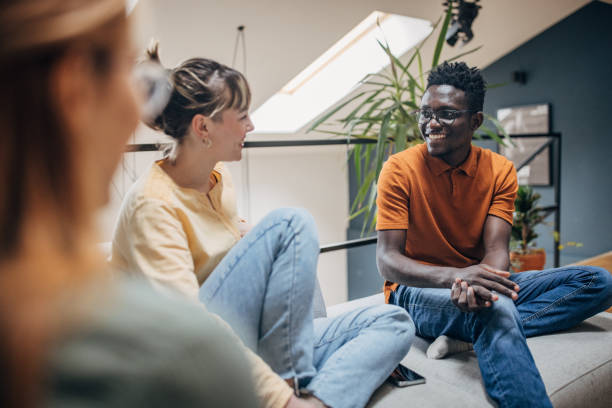 Multiracial group, young man and women sitting together in modern apartment.