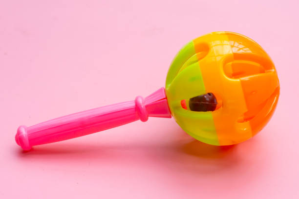 Colorful baby rattle on pink background