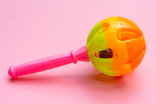 Colorful baby rattle on pink background