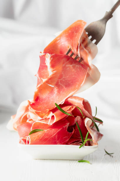 istock Prosciutto with rosemary on a white wooden table. 2148081204