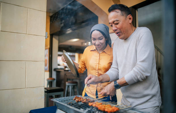 uomo anziano cinese asiatico che si diverte a imparare preparando l'esperienza satay nel ristorante locale di penang - asian culture barbecue chicken smoke foto e immagini stock