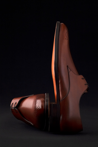 Close-up of brown leather men's shoes on black background.