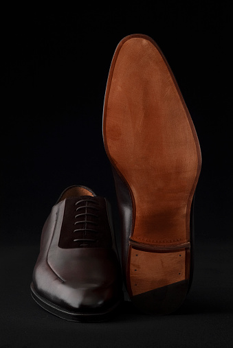 Close-up of brown leather men's shoes on black background.