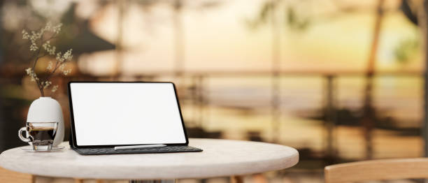 istock A digital tablet mockup on a round table with a blurred background of a sunset beach view. 2148082951