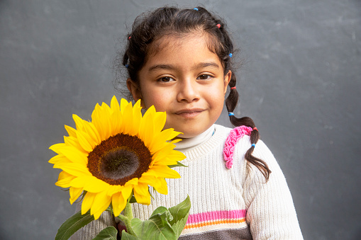 A cute young girl holding a sunflower