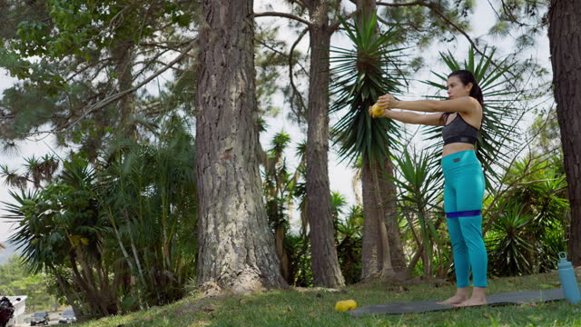 Hispanic pregnant young woman doing exercises with dumbbells outdoors