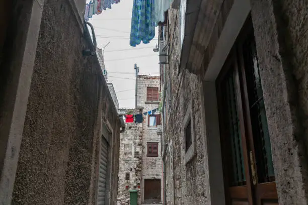 Multi-level flats buildings in narrow lane with laundry high-up drying in historic European city of Split in Croatia.