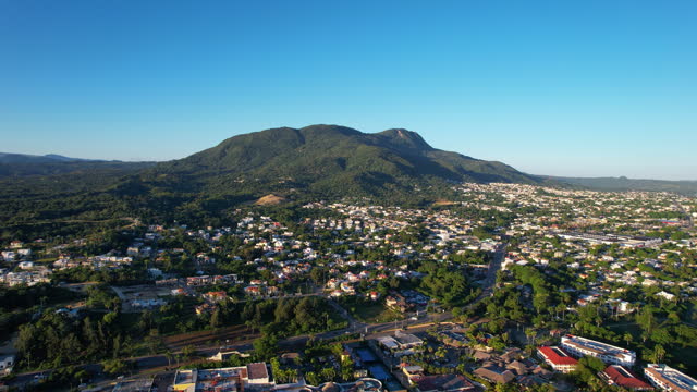 Charming quaint city of Puerto Plata during golden sunset on Dominican Republic. Green Mountain against blue sky. Aerial wide shot.