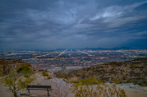 City lights of Phoenix, Arizona USA under dramatic skies at dusk, seen from South Mountain.