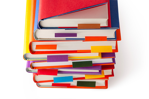 Stack of colored books with bookmarks on white background. Photo with clipping path.