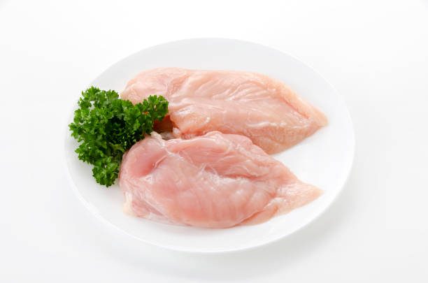 istock Raw Chicken breast with parsley on a  dish on white background 2148094669