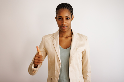 Portrait of beautiful young black woman on white background giving a thumb up gesture