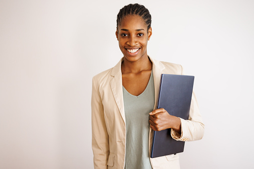 Portrait of beautiful young black woman on white background holding laptop and smiling to camera