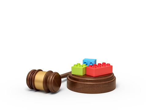 3d rendering of colorful lego pieces on round wooden block and brown wooden gavel