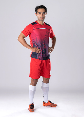 Male footballer wearing athletic uniform and shoes, standing still, confident posture according to athlete personality on a white background in the studio.