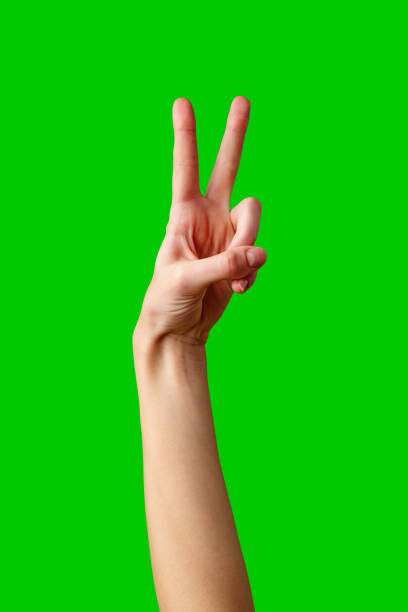 istock Hand Making Peace Sign Gesture Against Vibrant Green Background 2148098656