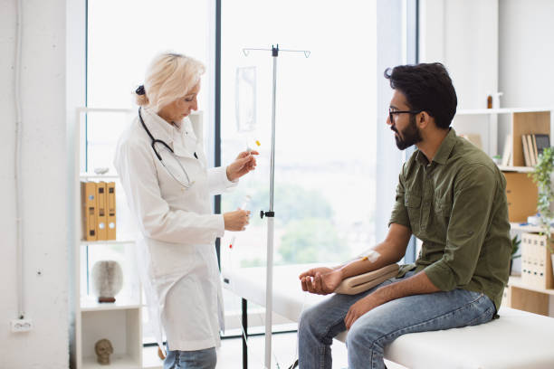 istock Bearded man receiving chemotherapy looking at nurse preparing a dropper. 2148098736