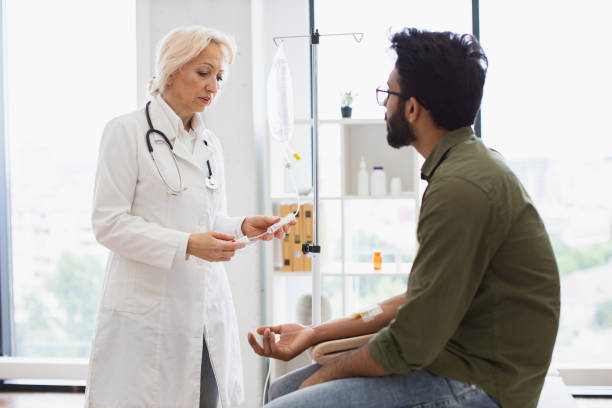istock Bearded man receiving chemotherapy looking at nurse preparing a dropper. 2148098751