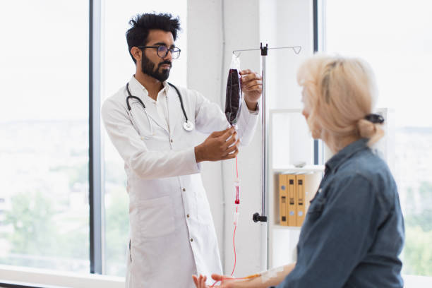 elderly woman receiving blood transfusion looking at medical doctor. - iv pump imagens e fotografias de stock