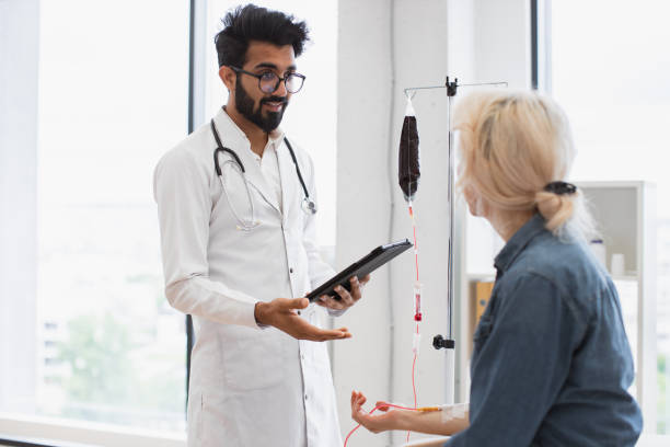 old woman with cancer looking at doctor with tablet. - iv pump imagens e fotografias de stock