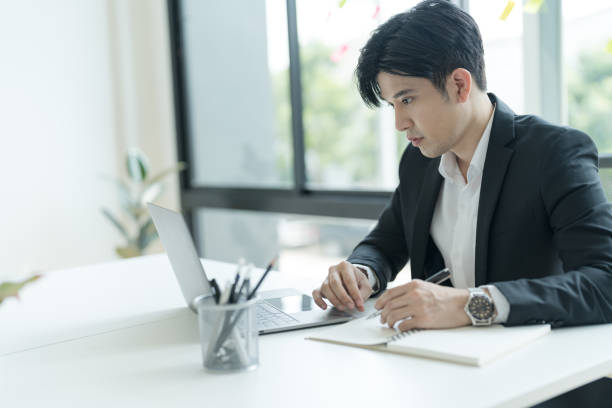 istock Young businessman opening a notebook View emails from customers sent. and write down the details. 2148098864