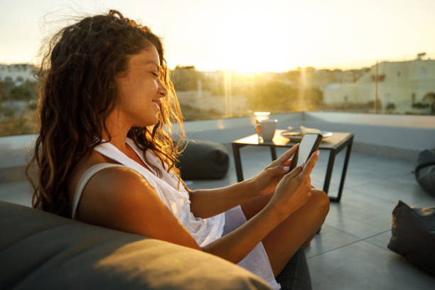 istock Relaxed woman using mobile phone on a terrace. at sunset 2148099056