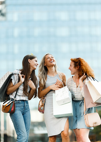 Group of happy women communicating during shopping day on the city street. Copy space.