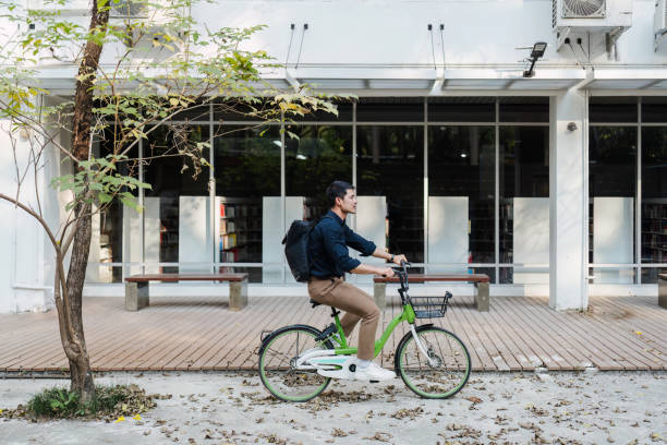 istock Young businessman ride bicycle to work to reduce global warming through the park. Eco friendly concept 2148100364