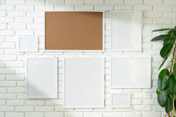 istock Varied Sized Photo Frames Displayed on a White Brick Wall 2148101096