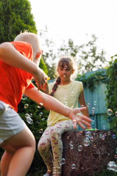 istock Playing, garden and children blowing bubbles for entertainment, weekend and fun activity together. Recreation, outdoors and siblings with a bubble toy for leisure, childhood and enjoyment in summer 2148101509