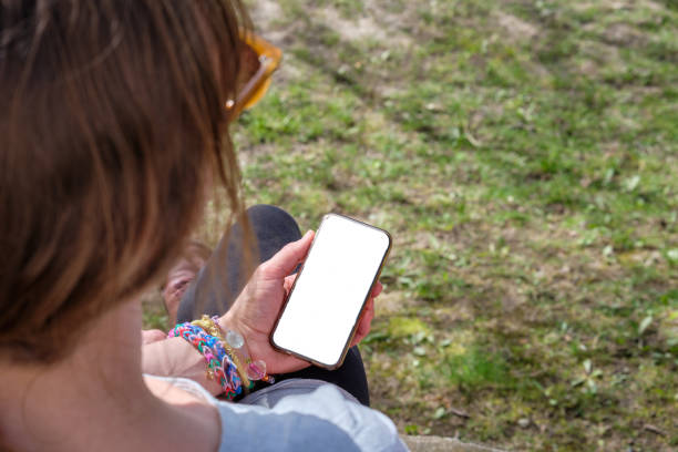 istock Mid adult woman looking at mobile phone screen while sitting outside 2148102191