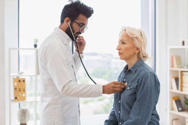 istock Adult man using stethoscope while elderly woman sitting on exam couch. 2148102262